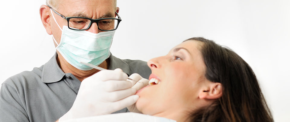 Zahnarzt Andreas Jordan prüft mit der Zahnsonde die Zähne einer Patientin